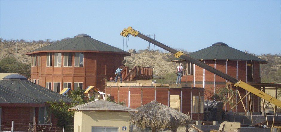 Suburban homes with dark roofs and a yellow construction crane in the background