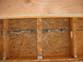 Wooden crate interior with a metal chain and turnbuckle brace across the center.