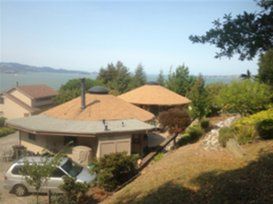 Houses with terracotta roofs on a hillside overlooking the sea under a clear sky