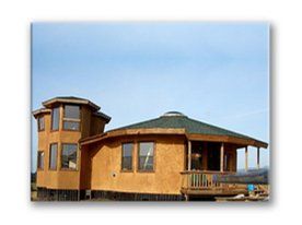 Tan house with green roof and tower against a blue sky