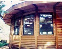 Wooden cabin exterior with a curved roof and several dark-framed windows
