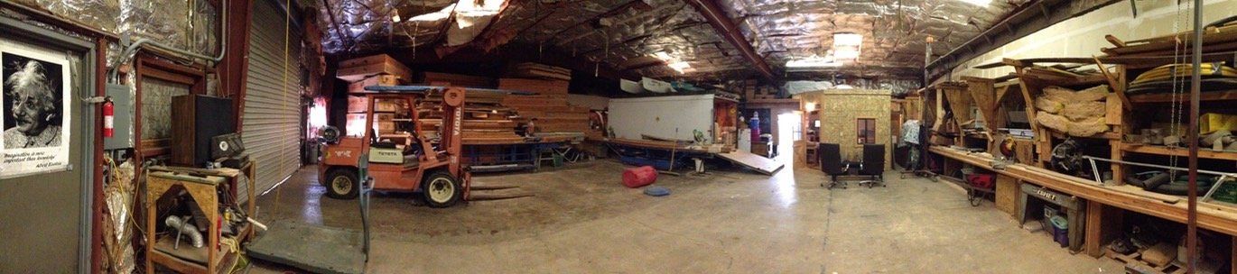 Dim industrial workshop with a red vintage car, tools, and shelves under bright overhead lights