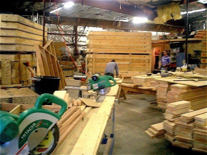 Stacked lumber and woodworking machinery inside a busy lumberyard workshop