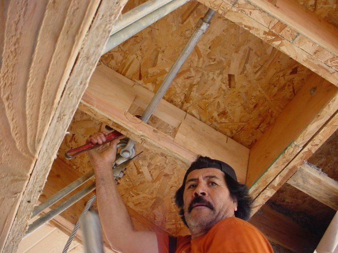 Man using a power drill to install framing in an unfinished wooden ceiling