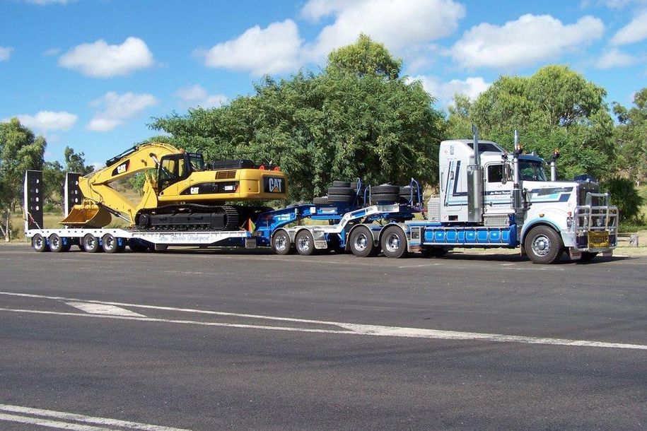 back view of long heavy industrial wood carrier cargo vessel truck trailer with big timber pine