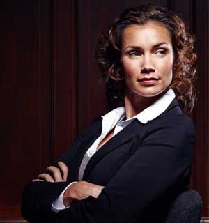 Confident professional in a dark blazer with arms crossed against a dark red background