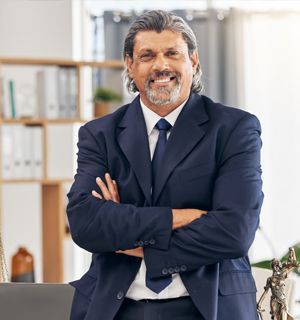 Smiling professional in a navy suit with arms crossed in an office setting