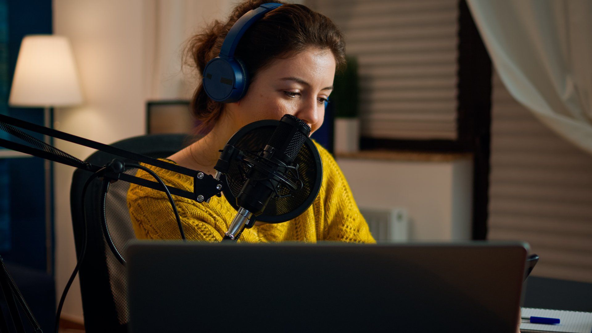 Blogger feliz leyendo mensajes de fanáticos que usan teléfonos inteligentes sentados en el estudio de podcasts en casa durante la transmisión en vivo Blogger feliz leyendo mensajes de fanáticos que usan teléfonos inteligentes sentados en el estudio de podcasts en casa durante la transmisión en vivo