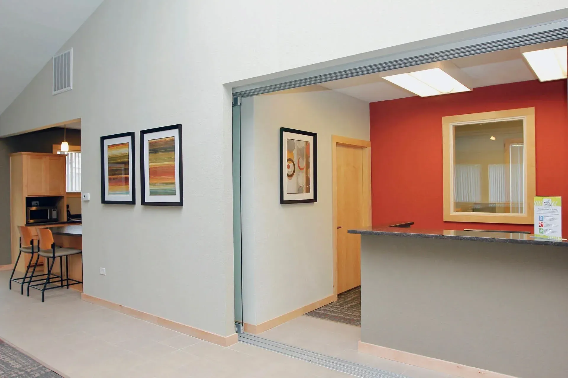 Thumbnail 6 of 51 - A hallway with a red wall and two framed pictures on the wall.