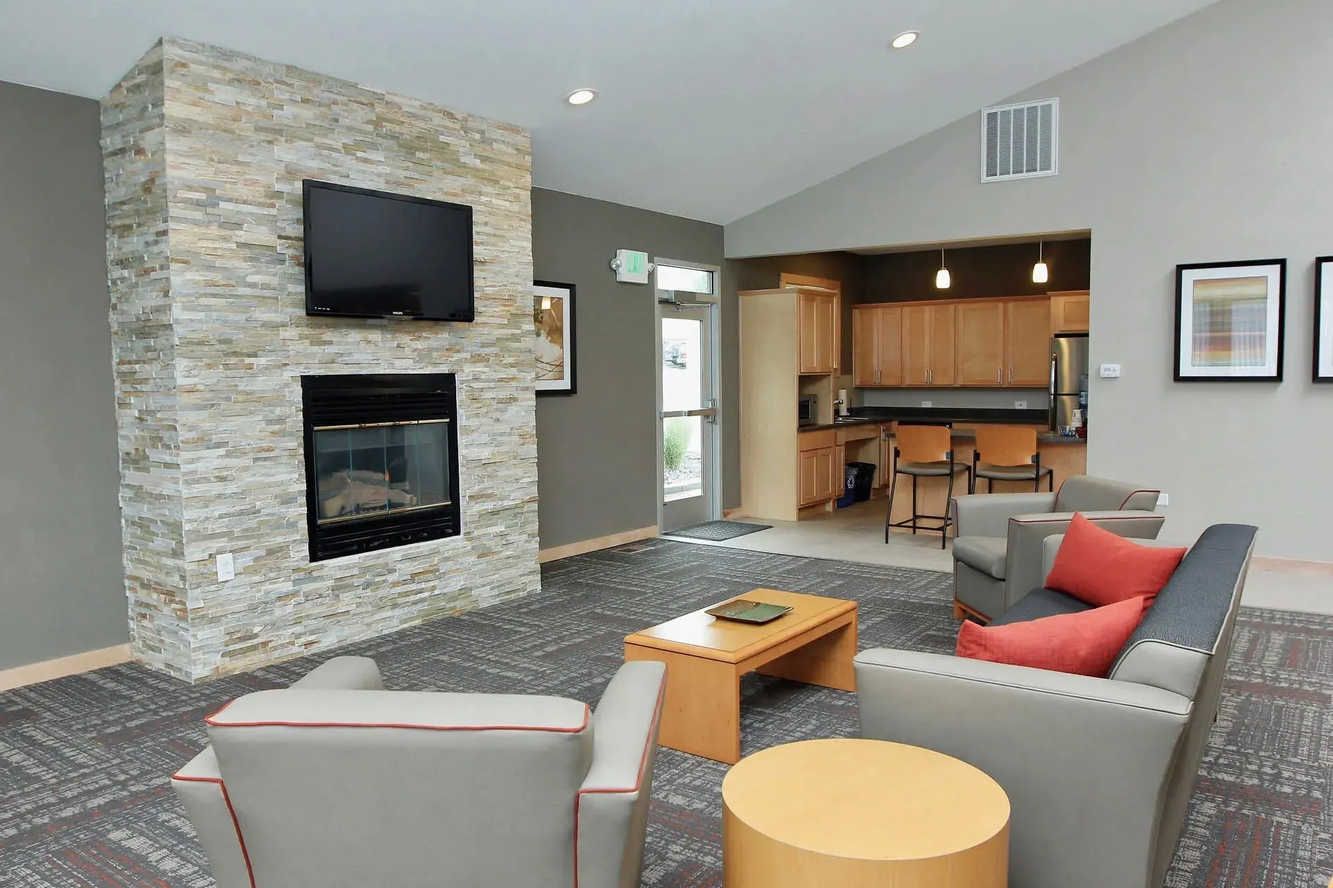 Thumbnail 3 of 51 - A living room with a stone fireplace and grey couches.