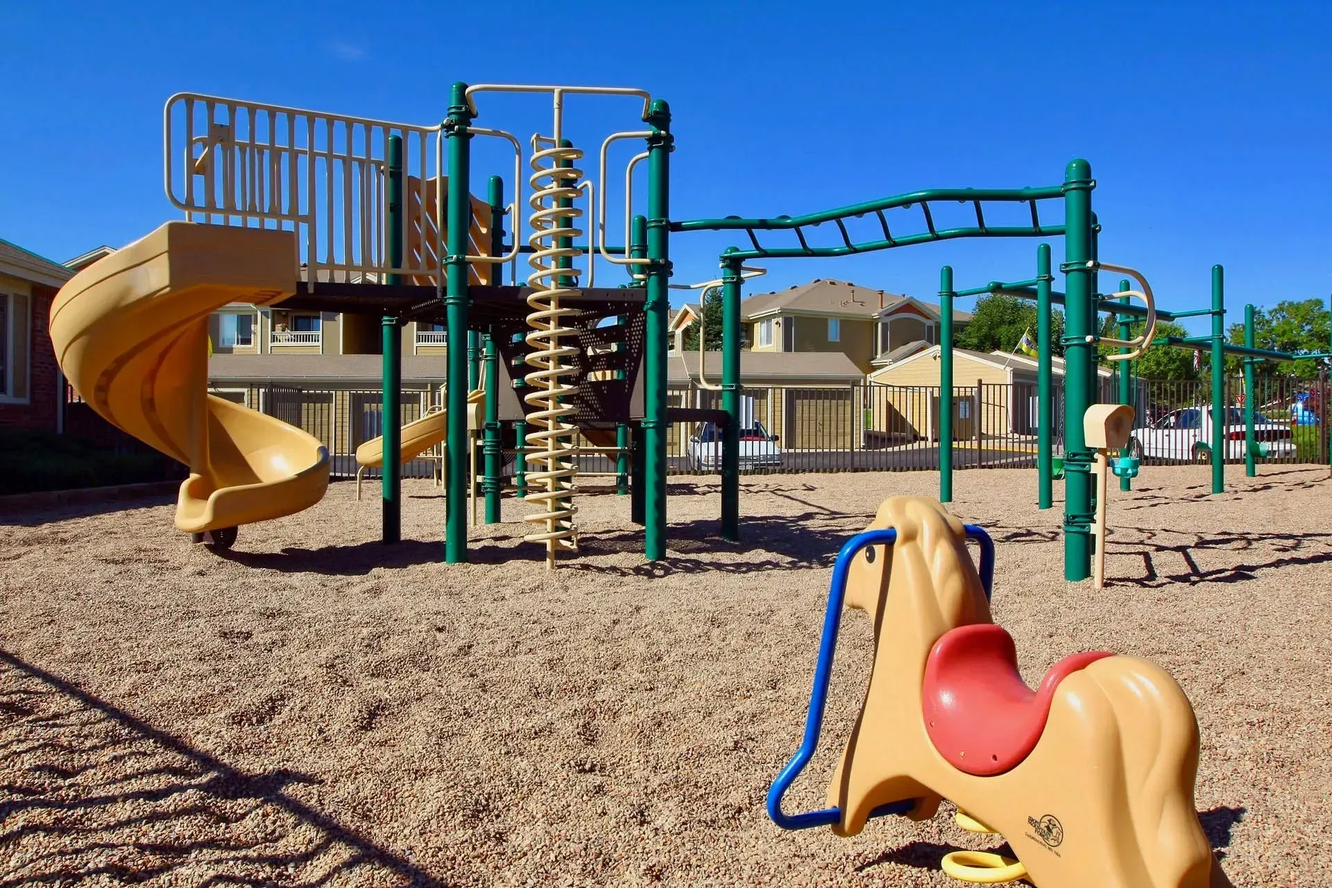 Thumbnail 29 of 51 - A playground with a yellow slide and a green monkey bar.