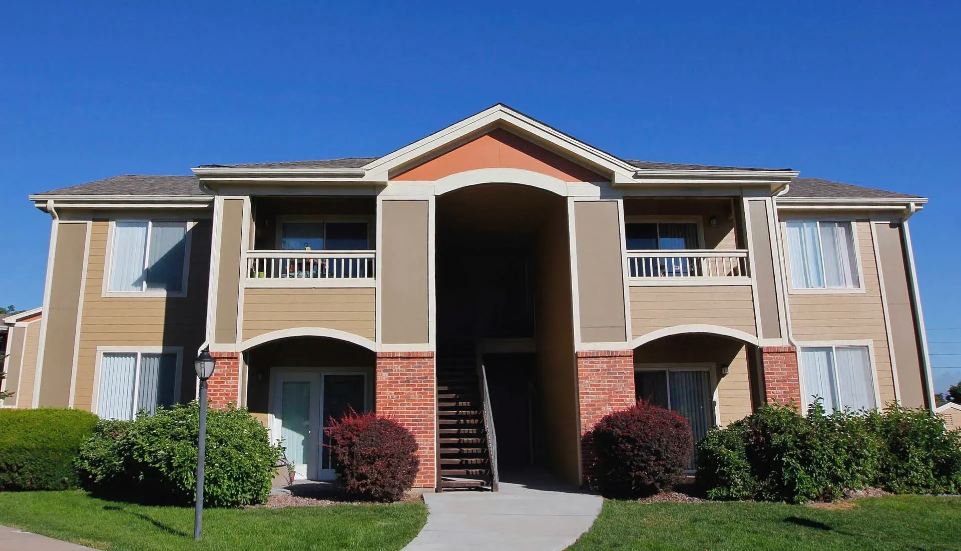 Thumbnail 43 of 51 - A large, beige apartment building with a red brick entrance.