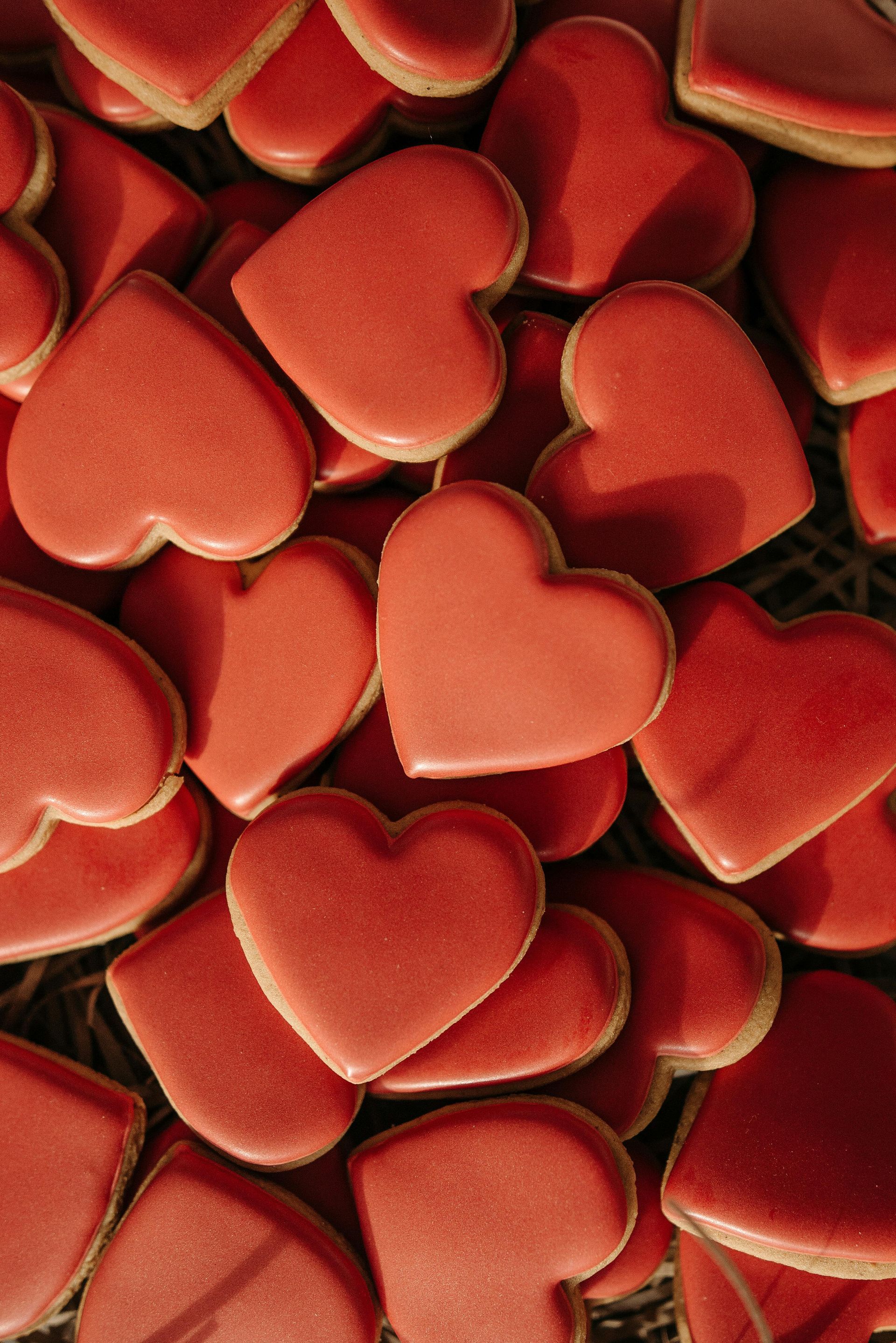 Red heart-shaped cookies, piled closely together.