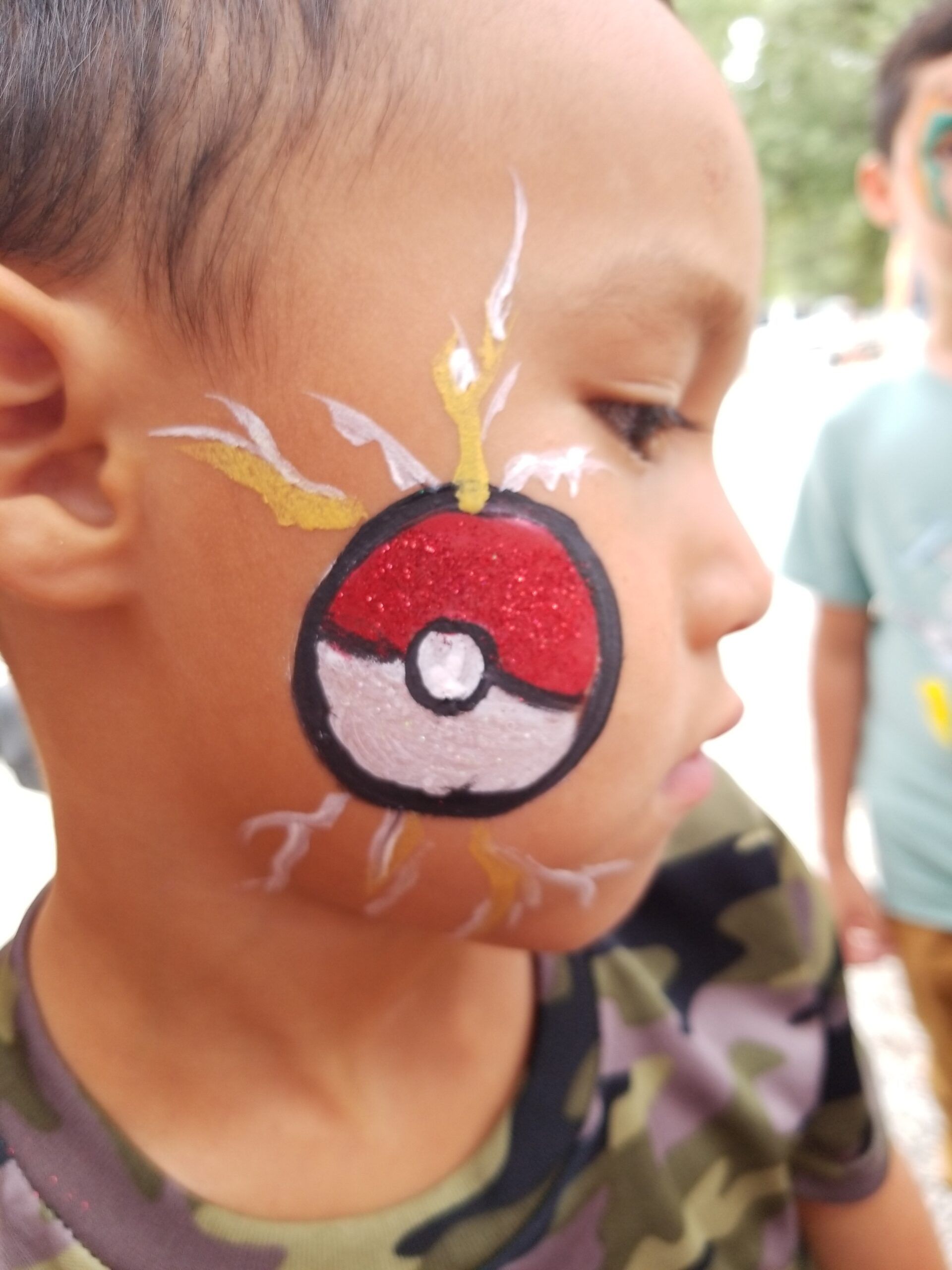 A young boy has a pokemon ball painted on his face