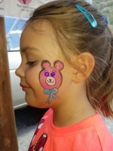 A little girl with a teddy bear painted on her face.