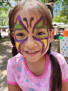 A little girl with her face painted like a butterfly.