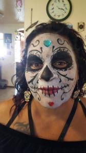 A woman with sugar skull makeup on her face is standing in front of a clock.