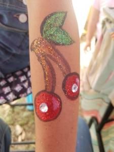 A person has a tattoo of two cherries on their arm.