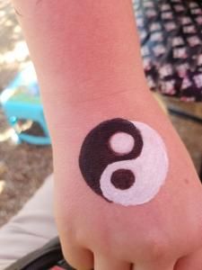 A person has a black and white yin yang symbol painted on their wrist.