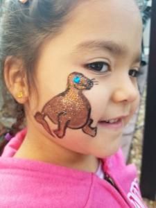A little girl with a seal painted on her face.