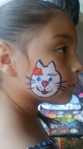 A little girl has a cat face painted on her face.