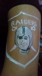 A person has a raiders logo painted on their arm.