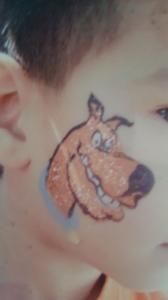 A child has scooby doo painted on their face.