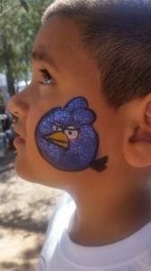 A young boy has an angry bird painted on his face
