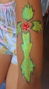 A person has a green leaf and a red flower painted on their arm.