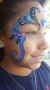 A young girl with a face painted design on her face.
