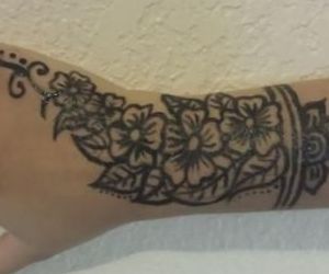 A woman 's arm with a tattoo of flowers and leaves on it.