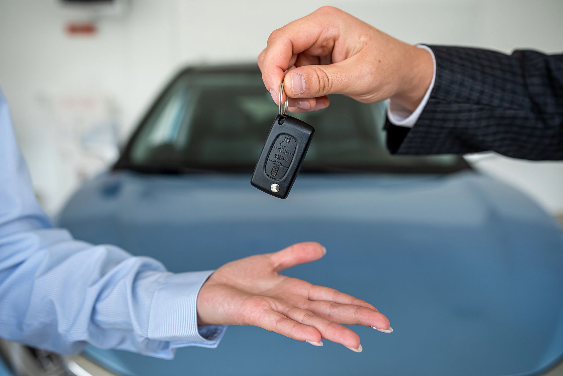 La chiave dell'auto è stata consegnata davanti a un'auto blu.