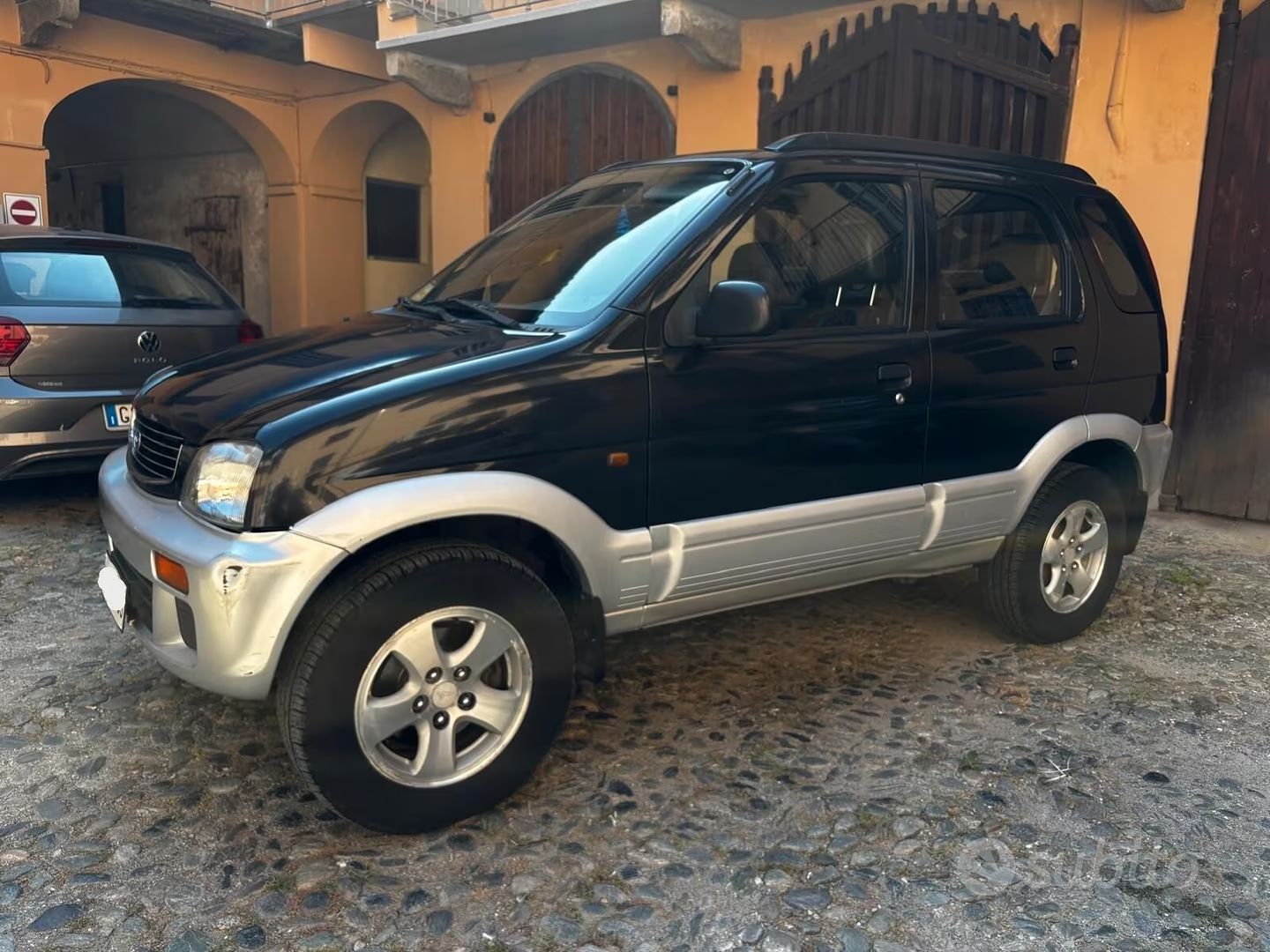 Un SUV nero e argento è parcheggiato nel vialetto di una casa.