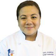 Portrait of a chef in a white coat, smiling against a white background.