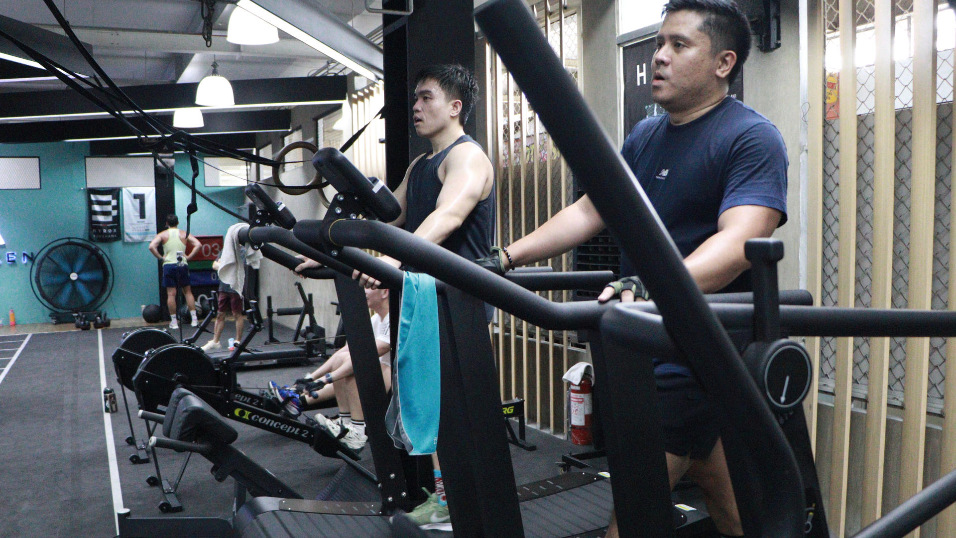 People exercising on treadmills in a gym, with mirrors and equipment visible.