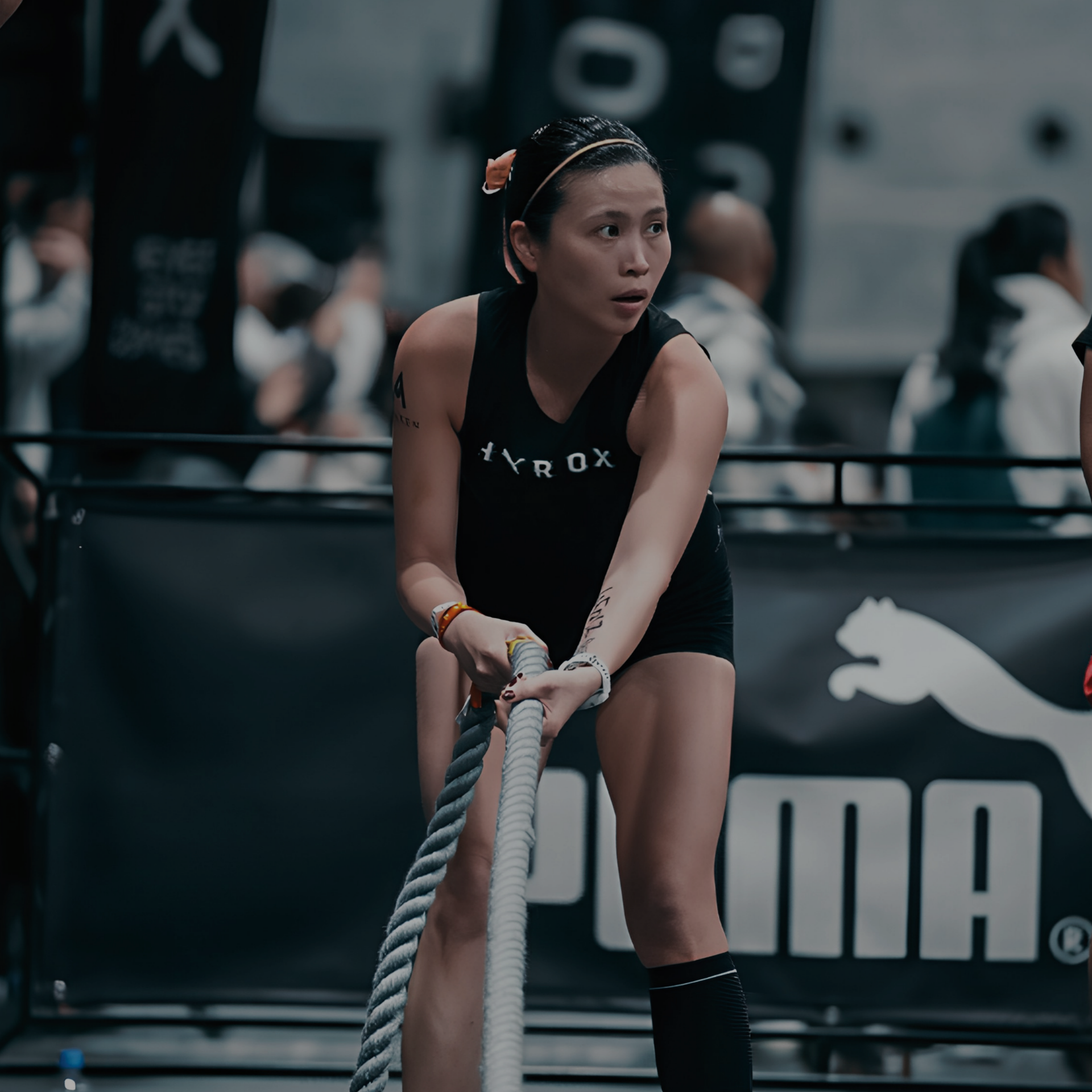 Athlete gripping a battle rope during a workout competition, focused in a gym setting