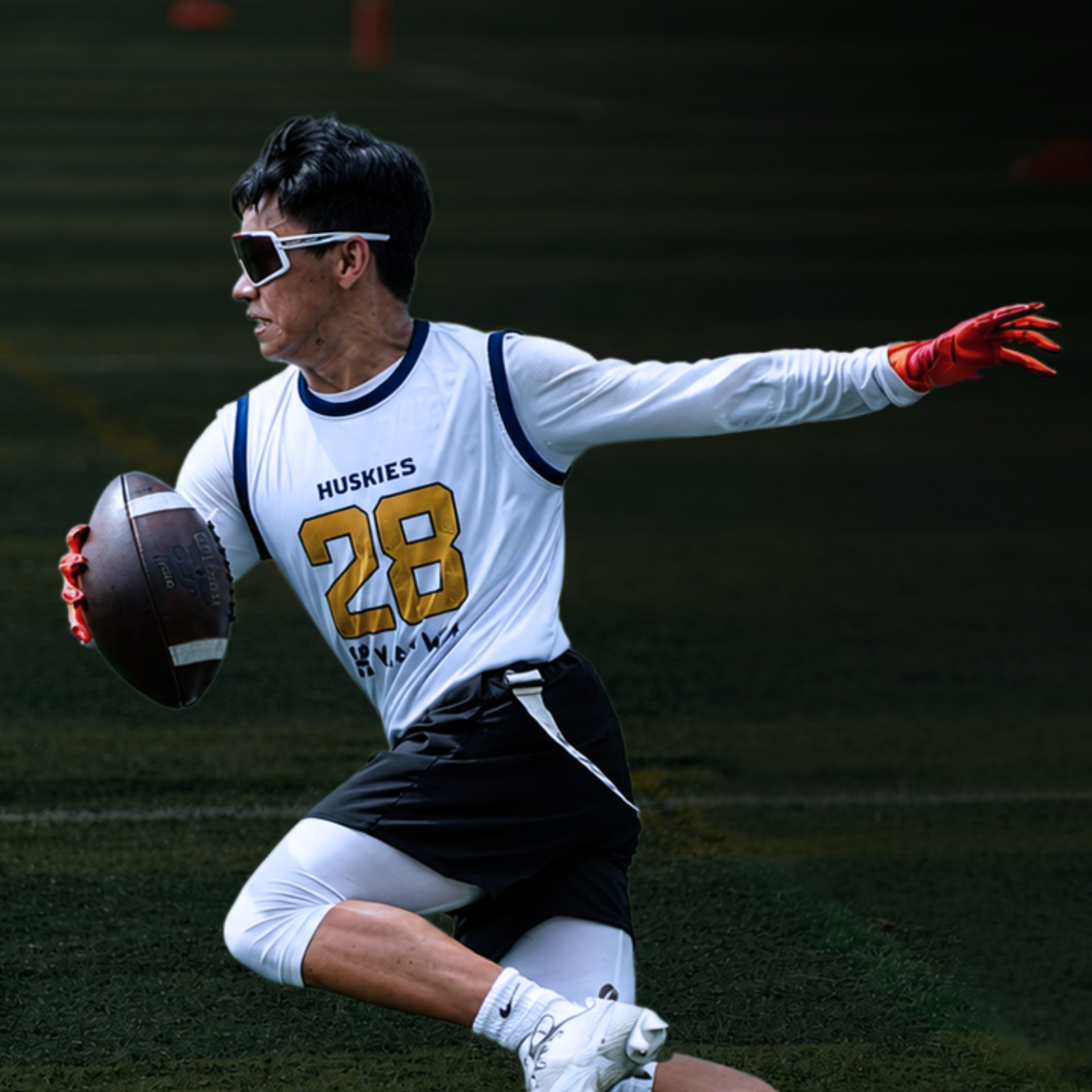 Football player in white and black uniform, number 28, running with the ball on a field, red gloves extended