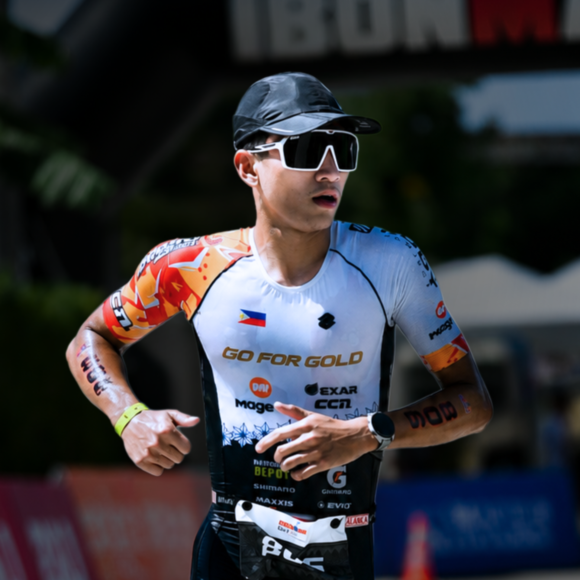 Cyclist in black cap and sunglasses running shirtless in a white race jersey at an outdoor event