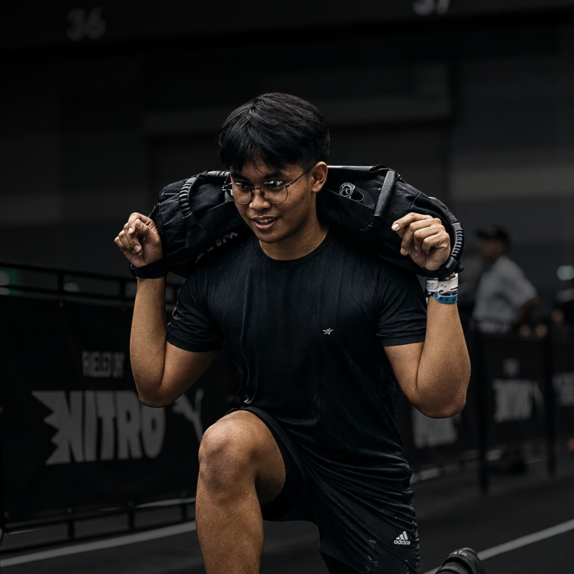 Athlete pulling battle ropes in a dark gym, focused and sweating.