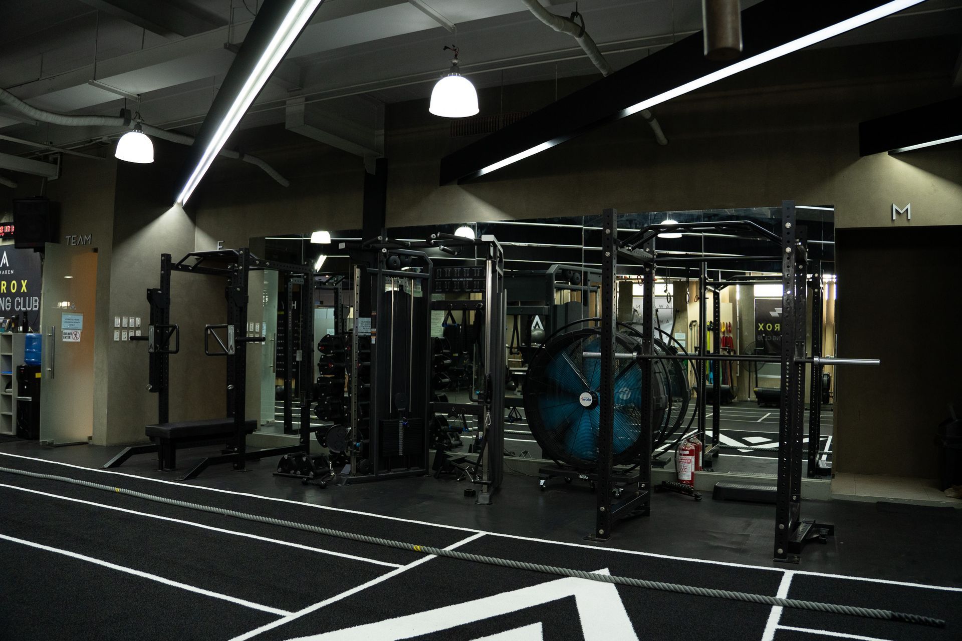 Empty gym interior with weight machines, cable equipment, and overhead lights