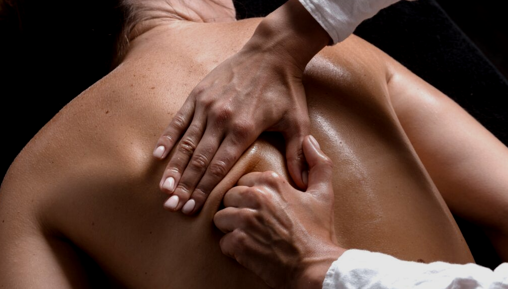 A person receiving a back massage with hands applying firm pressure to the skin.