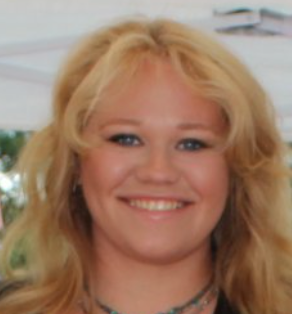 Woman with blonde hair smiling, wearing a necklace.
