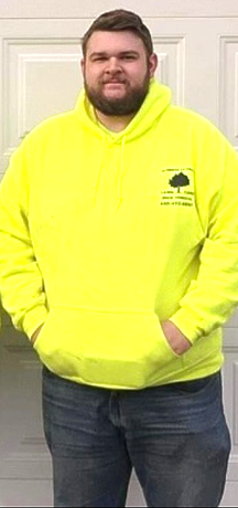 A person wearing a neon yellow hoodie and blue jeans stands in front of a white door.