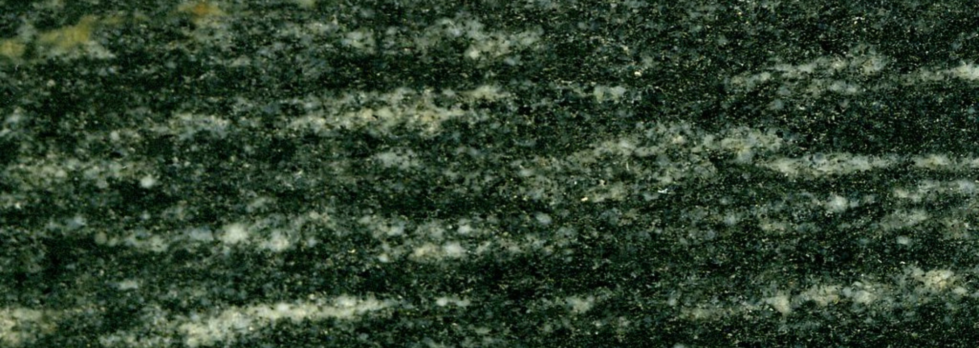 Dark green rock with white and light green horizontal bands, likely a type of stone.