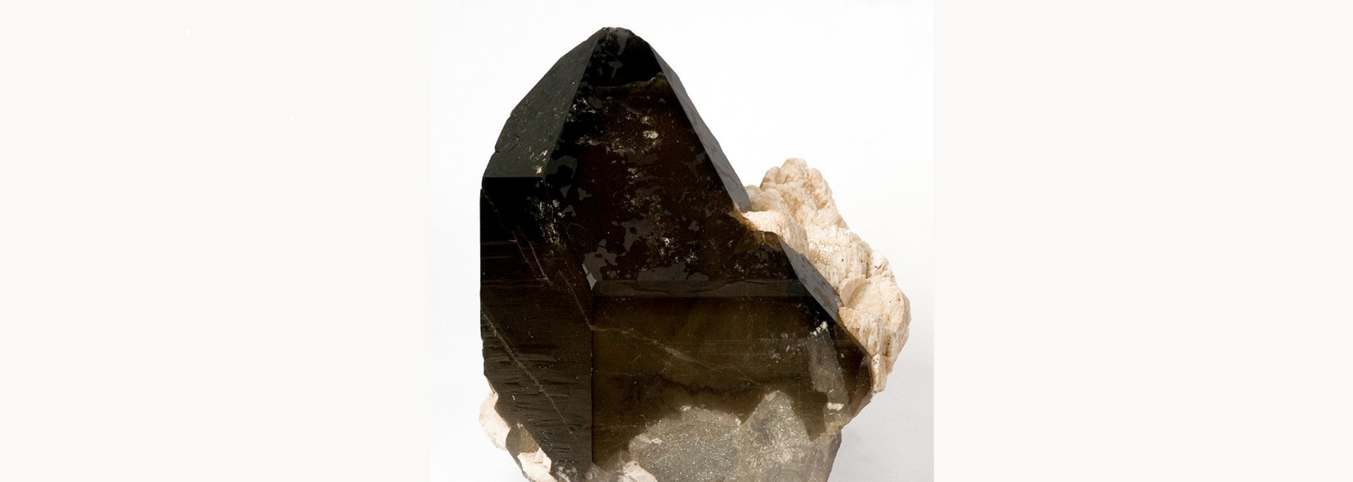 Smoky quartz crystal, dark brown and transparent, against a white background.