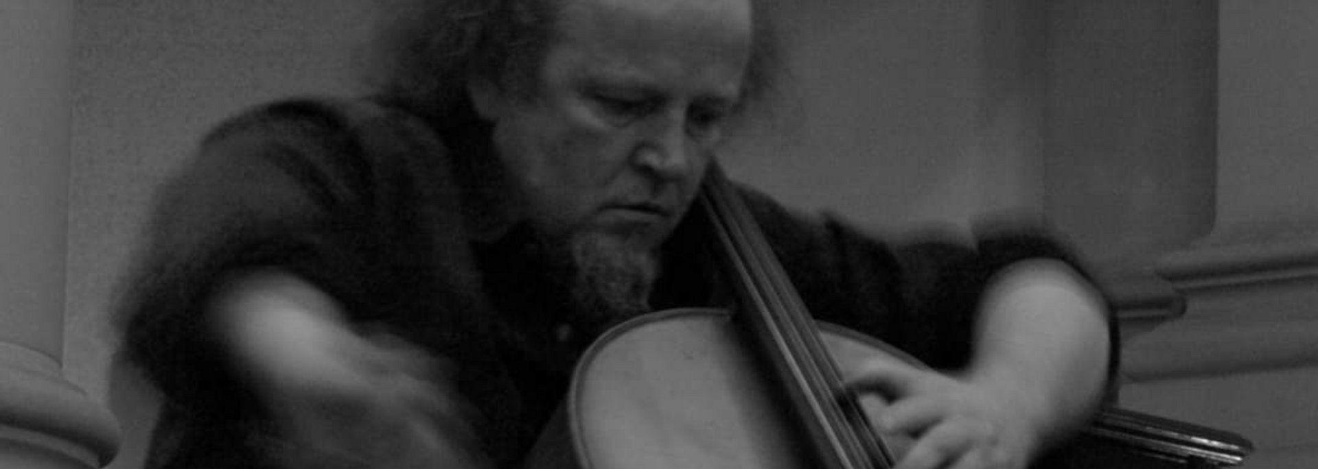 A musician playing a cello, close-up, black and white photo.