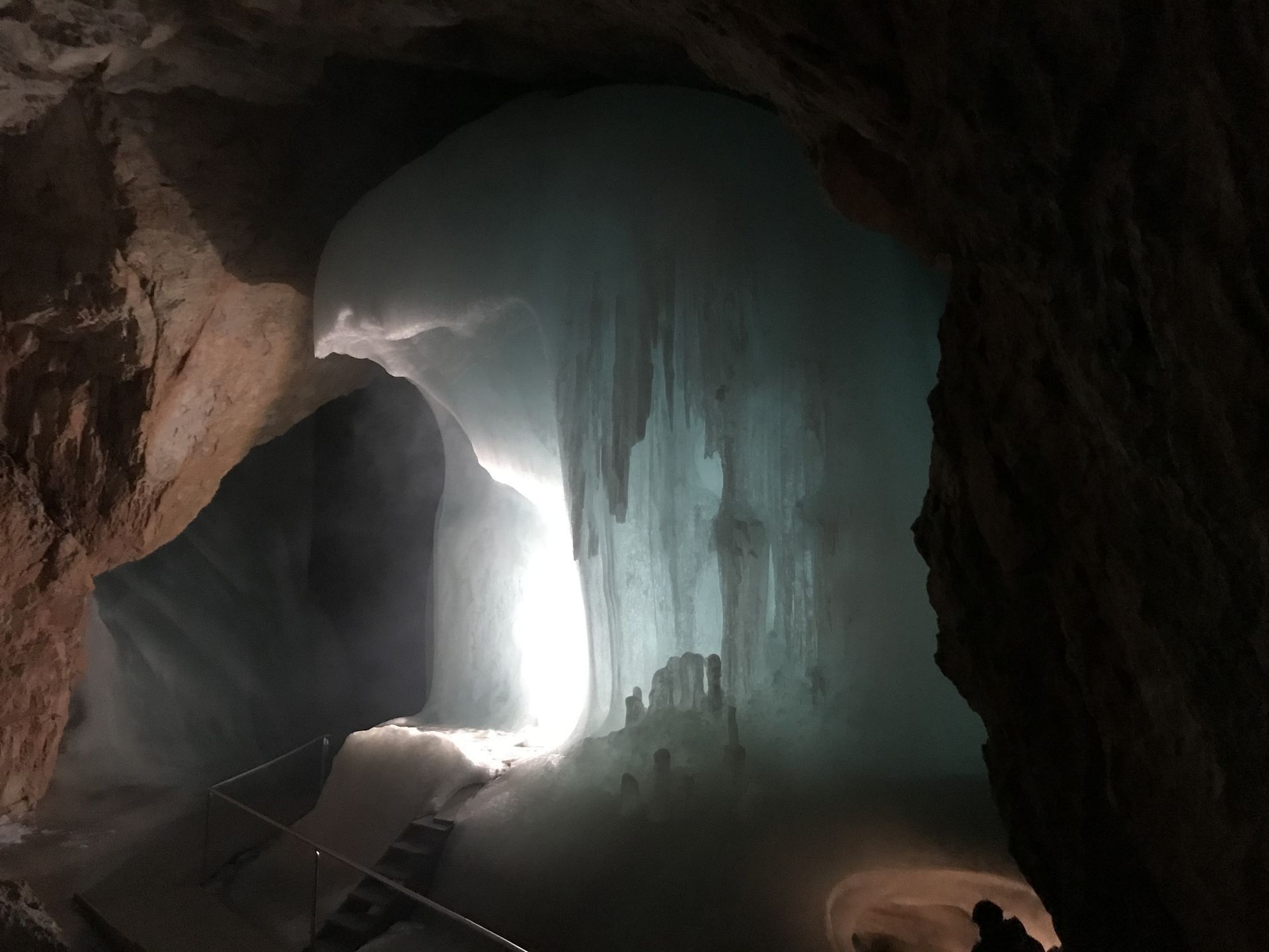 Ice cave with a large blue-white ice formation and a light opening.