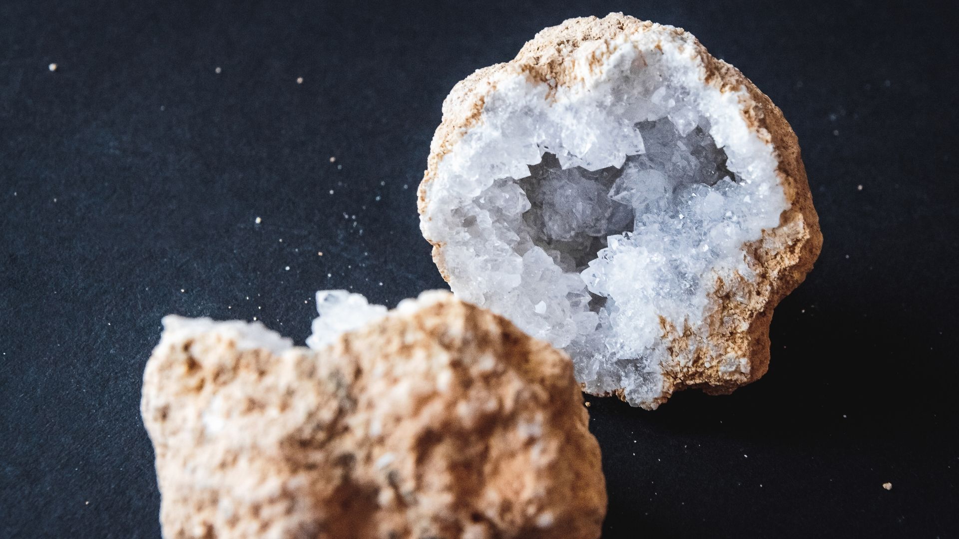 Split open geode revealing white crystalline interior. Brown exterior on black surface.