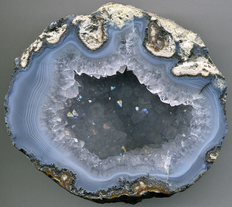 Cut open geode, revealing concentric blue and white agate bands and a crystal-lined cavity.
