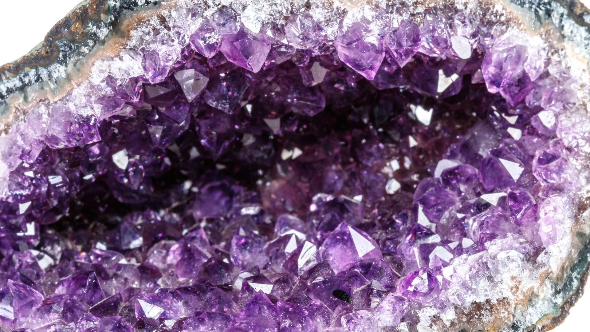 Amethyst geode, interior filled with purple quartz crystals, nestled in a grey and brown rock formation.